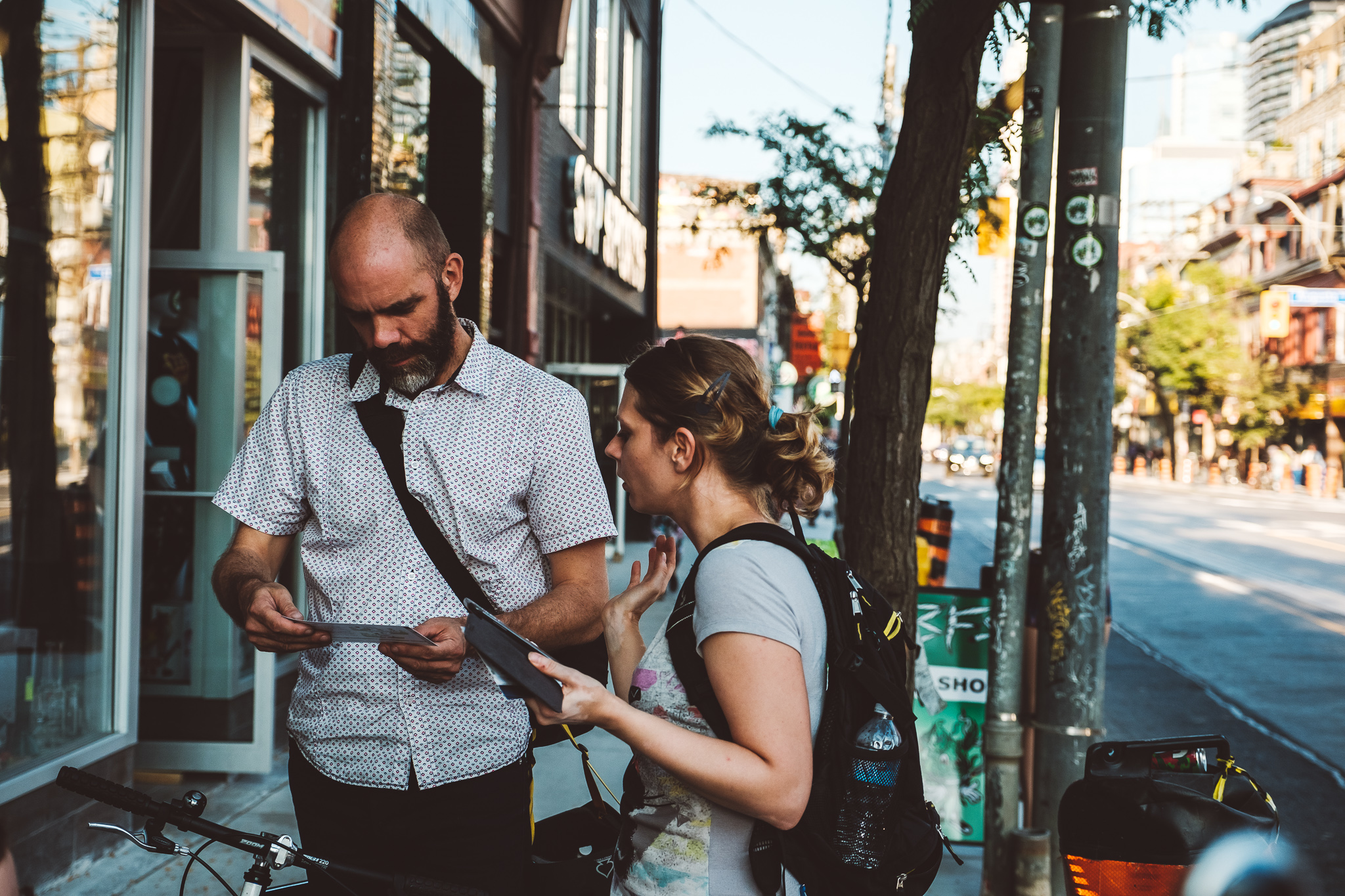 A Wheelmap ambassador talks to a passers-by on a sidewalk in Toronto and hands out a Wheelmap flyer.