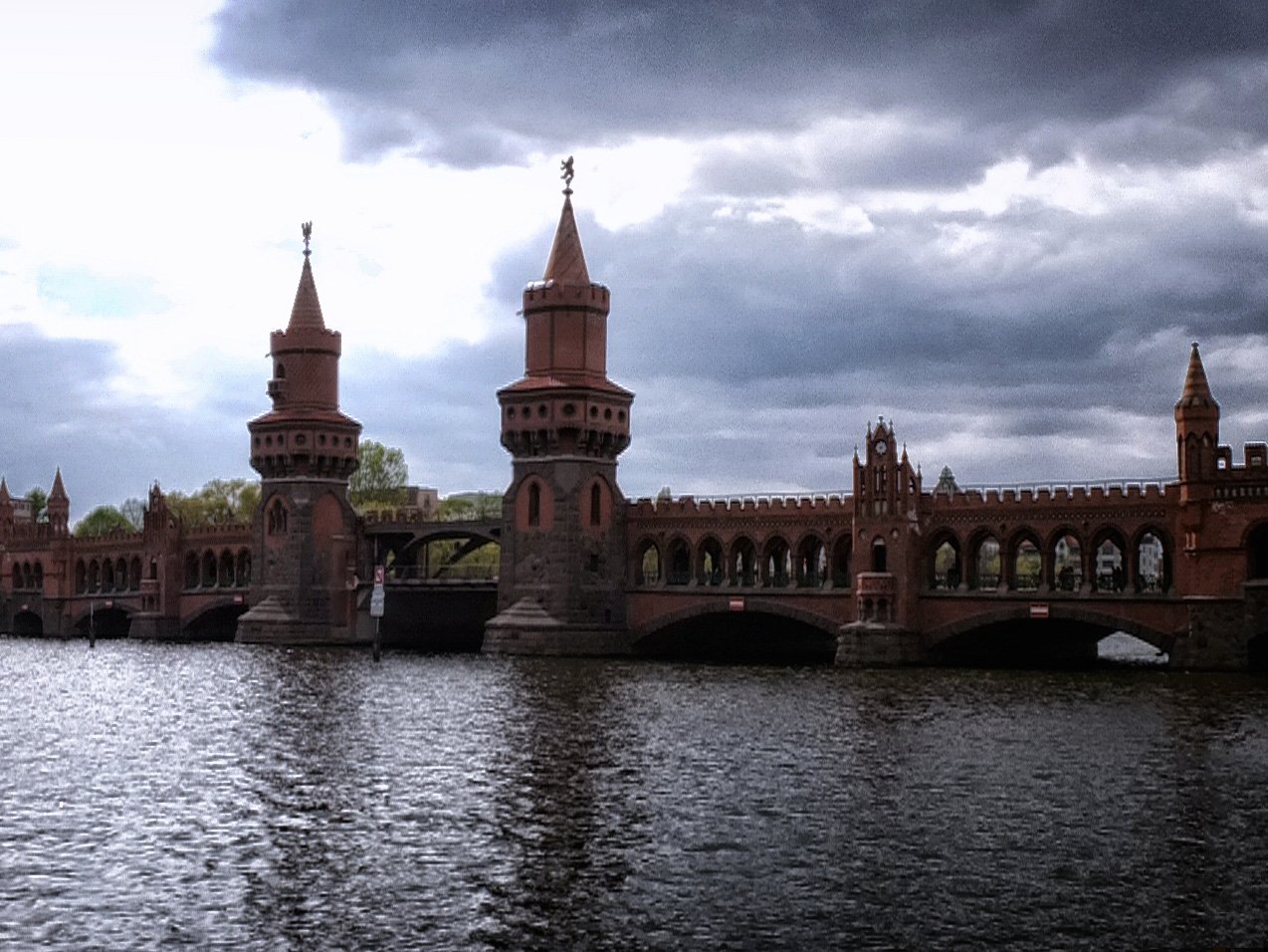 Die Oberbaumbrücke aus Backstein mit ihren zwei Türmen in Berlin an einem bewölkten Tag.