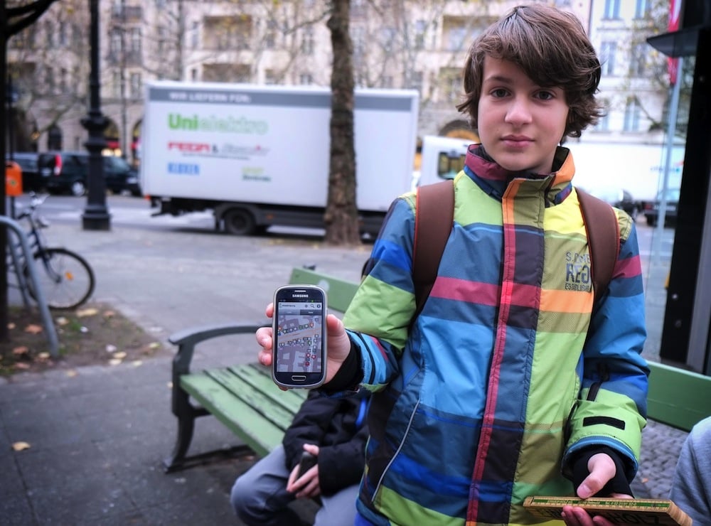 Foto von einem Kind, welches ein Smartphone in die Kamera hält, auf der die Wheelmap geöffnet ist.