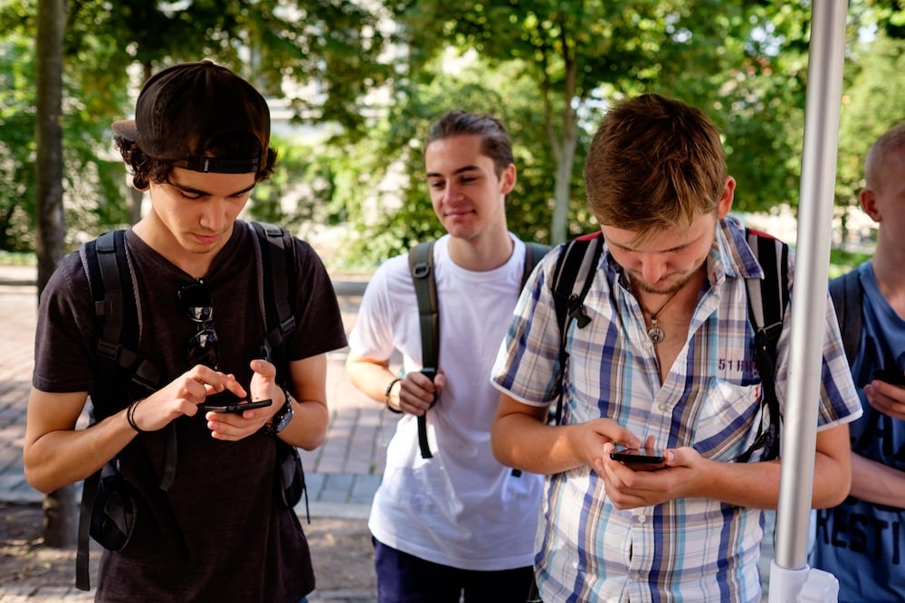 Zwei junge Männer tippen auf ihrem Smartphone herum
